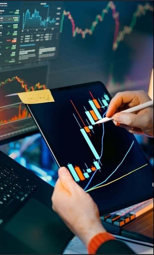 Professional trader analysing candlestick charts on multiple screens